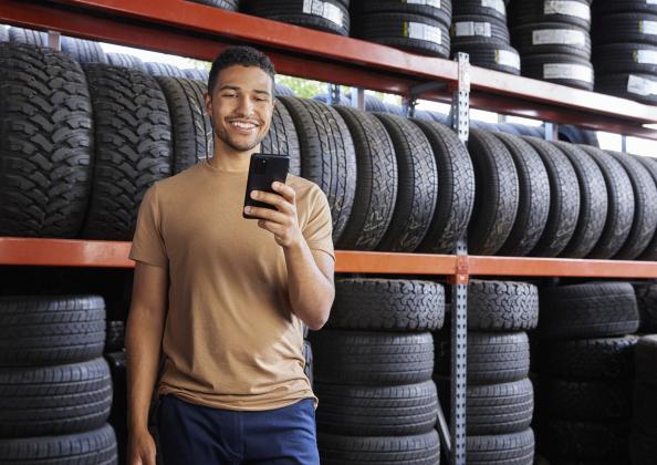 A man looking at his phone in a tire shop. 
